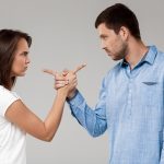 Young beautiful married couple posing over grey background.